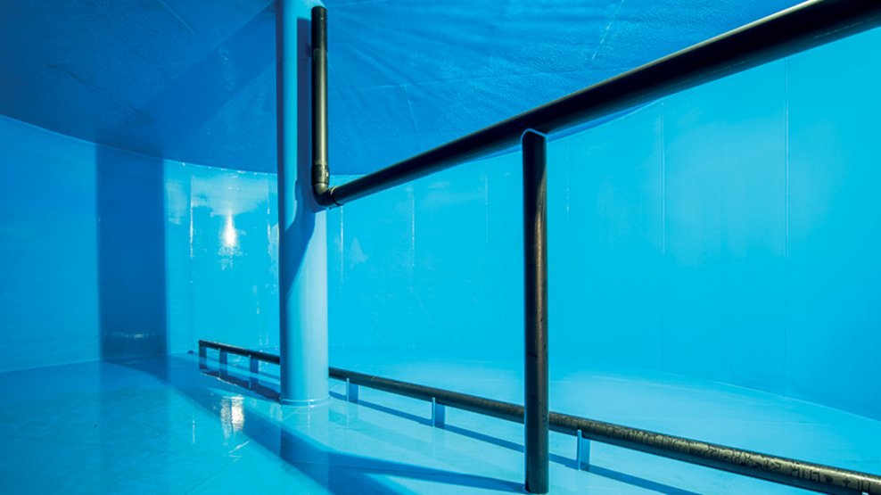 Blue-coated tank interior featuring vertical and horizontal piping and a reflective surface finish.