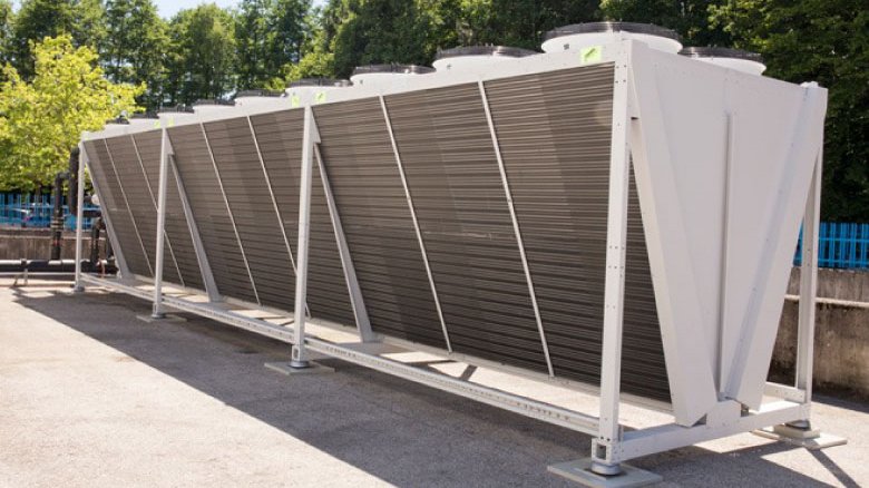 Multiple industrial cooling units with finned surfaces installed on paved outdoor area