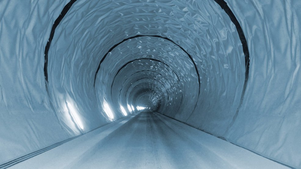 Long membrane-lined tunnel with illuminated side walls and a straight roadway extending into the distance.