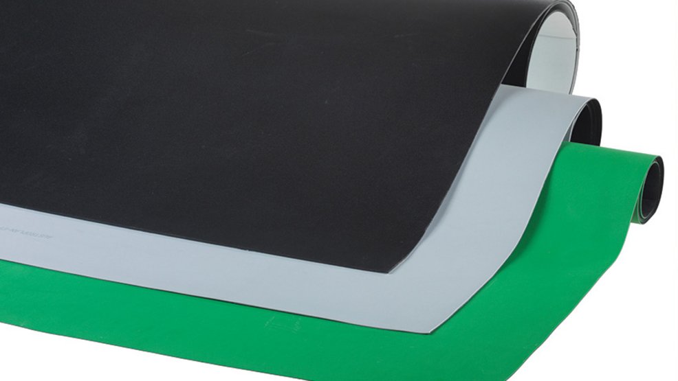 Multi-layer plastic sheets in black, gray, and green curve in smooth arcs against a light background.