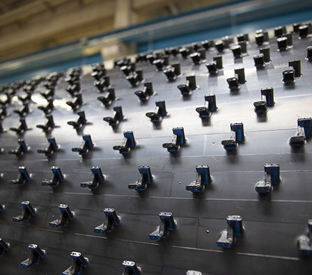 Black plastic panel with evenly arranged retaining elements in an industrial production environment.